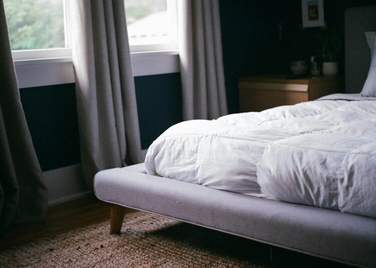 white bed by the window during daytime