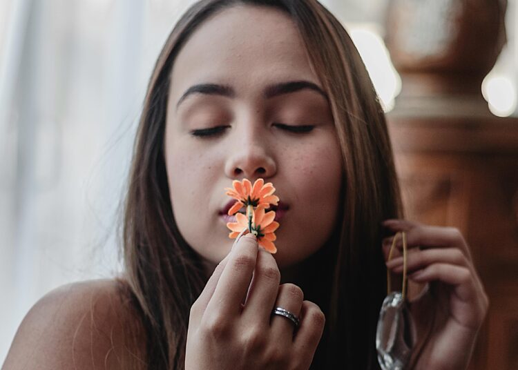 Portrait of woman kissing orange flowers